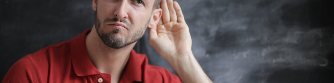 man in red polo shirt sitting near chalkboard
