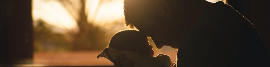 man carrying baby drawing their foreheads