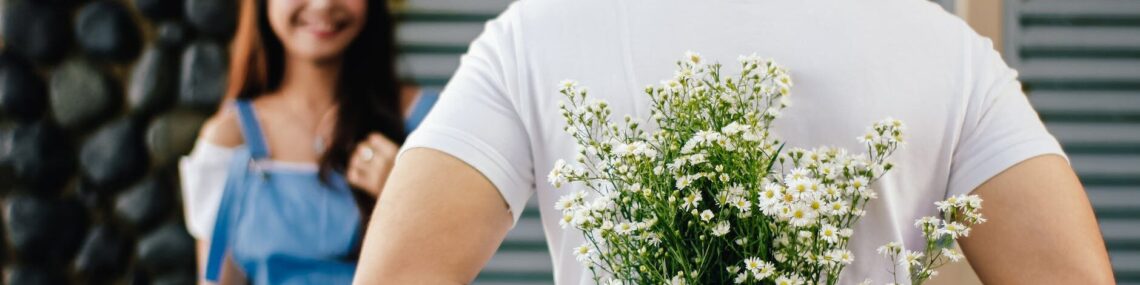 man holding baby s breath flower in front of woman standing near marble wall