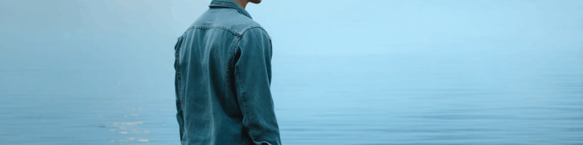 Man standing looking over the water intently